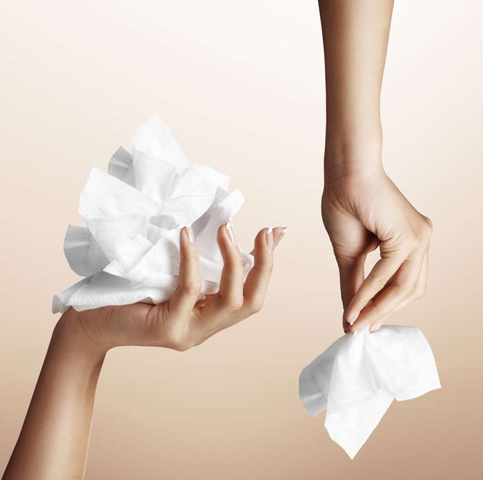 Two hands each holding tissues