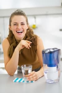 Woman smiling next to a water filtration pitcher